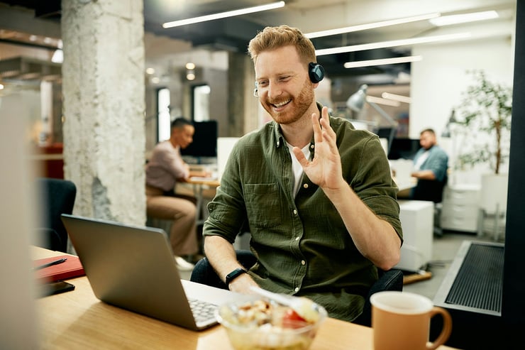 A male IT support desk employee from a managed IT services firm is seen greeting his client from a financial services organization during a morning video call, where he is providing support by troubleshooting an issue in Microsoft 365, highlighting the essential IT services managed service providers deliver to financial institutions—such as proactive support, issue resolution, and application management—to ensure smooth operations and uninterrupted productivity.