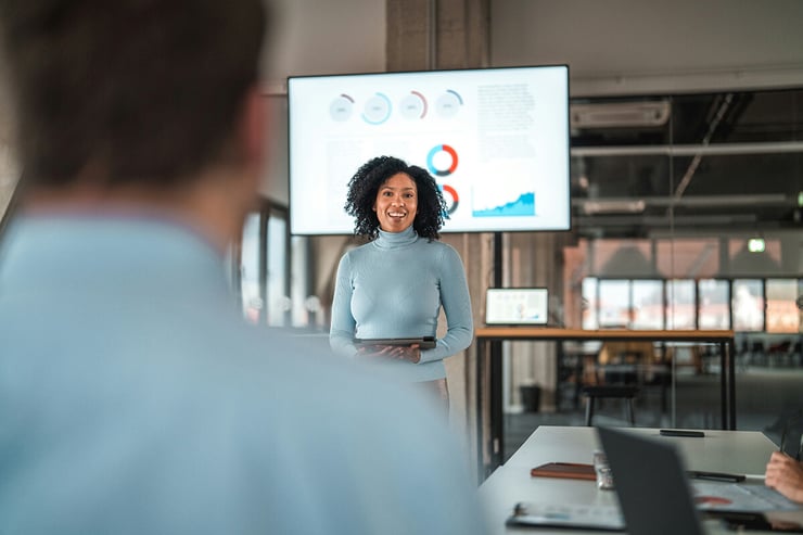 An insurance employee is seen using data visualization tools and PowerPoint to present an upcoming enterprise coverage benefits and incentives report to representatives from her enterprise client, highlighting the importance of choosing the right managed IT services provider for your financial institution—one that offers reliable application management, robust data security, and seamless support to ensure critical tools function flawlessly, enabling professionals to deliver impactful results to their clients.