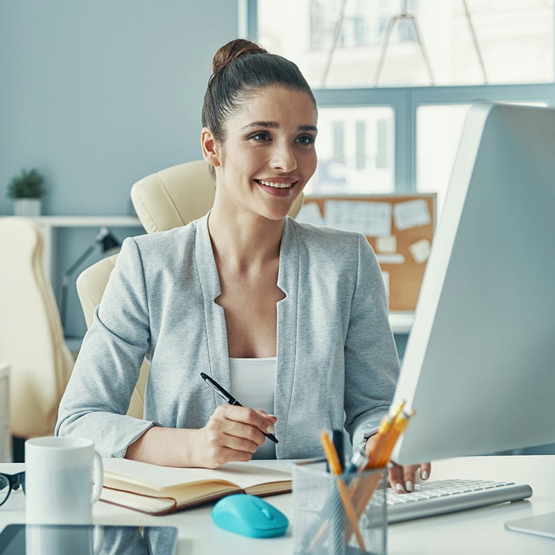 A woman in her office smiles as she securely and efficiently accesses workload applications with ease, thanks to the features offered by Microsoft Entra Permissions Management.