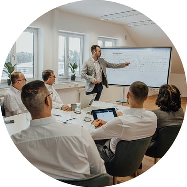 An IT consultant from Synergy Technical leads business and IT employees through a hands-on session where they explore Microsoft tools on their laptops, uncovering hidden features like AI-driven meeting summaries, Excel automation, and Loop collaboration to streamline daily tasks and boost efficiency.