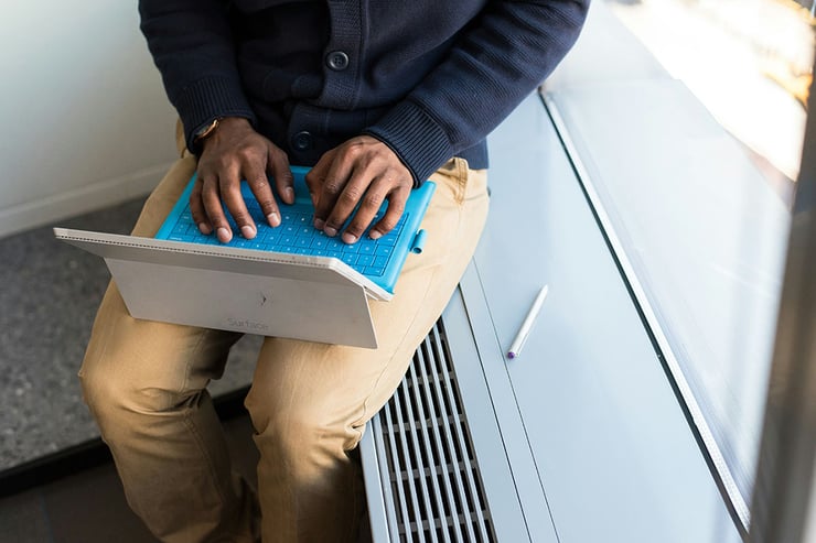 An employee sitting by the office window with a laptop.