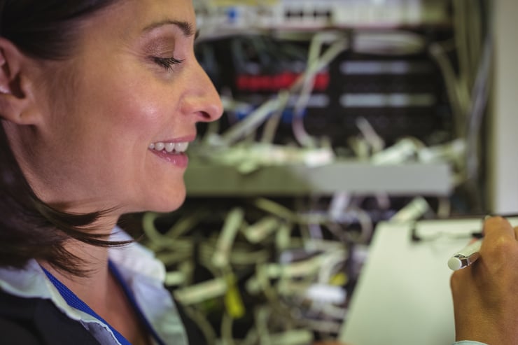 Technician maintaining record of rack mounted server on clipboard in server room