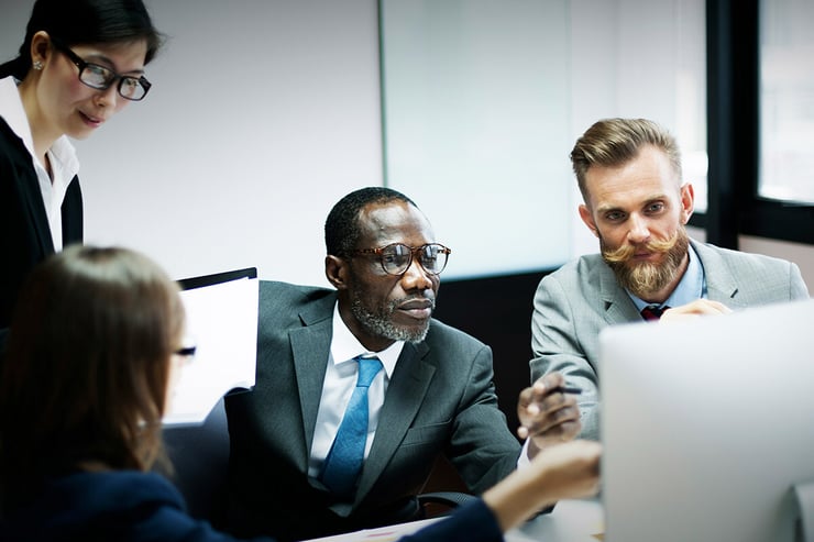 A male employee gathers with his colleagues around his desktop, showcasing Microsoft SharePoint on his screen as they collaborate on shared documents, leveraging their organization's Microsoft CSP partnership to ensure secure access, streamlined teamwork, and the right licensing for their business needs.