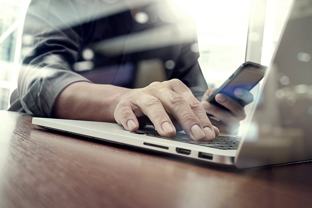 Man with smart phone and laptop in office