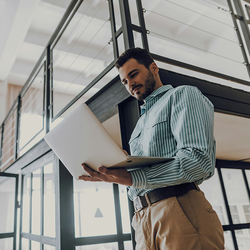 Standing with his laptop open, he reviews and updates an AI agent in Microsoft Copilot Studio, making real-time adjustments that improve responses without disrupting his workflow.